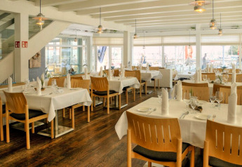 Bright, modern lodge dining area with set tables, wooden chairs, large windows, and a welcoming ambiance.