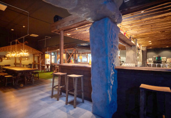 Gemütliches Lodge-Interieur mit rustikalen Holzmöbeln, Geweihleuchtern und einladender Barbereich.