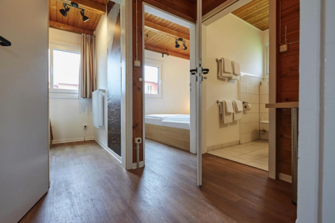 Ingresso di lodge moderno con pavimento in legno e bagno a Blockhouse «HiPr 4 Pers», Germania.