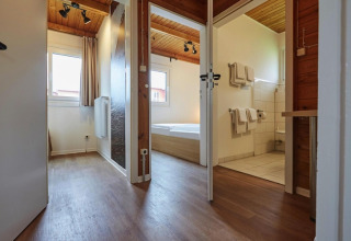 Inkomhal van moderne lodge met houten vloer en badkamer in Blockhouse «HiPr 4 Pers», Duitsland.