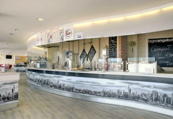 Cafetería moderna con menús y decoración de ciudad en Blockhouse «HiPr 4 Pers» en Alemania.