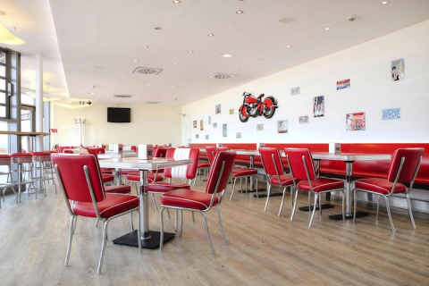 Cafetería retro en Blockhouse «HiPr 4 Pers» en Alemania, con sillas rojas y decoraciones en la pared.