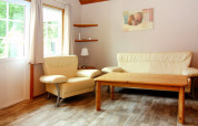 Helles Wohnzimmer mit cremefarbenem Sofa, Sessel und Holztisch im Holiday Park Markgrafenheide Warnemünde.