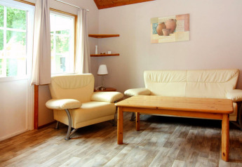 Soggiorno luminoso con divano e poltrona color crema, tavolo in legno al Holiday park Markgrafenheide Warnemünde.