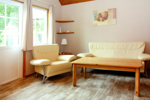Bright living area with cream sofa, armchair, wood floor and table at Holiday park Markgrafenheide Warnemünde.