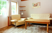Lichte zithoek met crèmekleurige zetel, fauteuil en houten tafel in Holiday park Markgrafenheide Warnemünde.