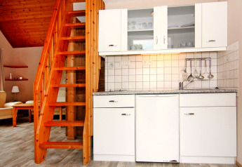 Cucina moderna con mobili bianchi e scala in legno, Holiday Park Markgrafenheide Warnemünde, Germania.