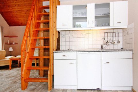 Modern lodge kitchen with white cabinets and a wooden staircase at Holiday Park Markgrafenheide Warnemünde, Germany.