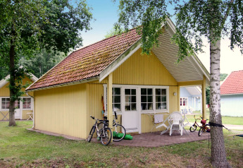 Gelbes Ferienhaus mit Terrasse, Fahrrädern und Kinderspielzeug im Ferienpark Markgrafenheide Warnemünde.