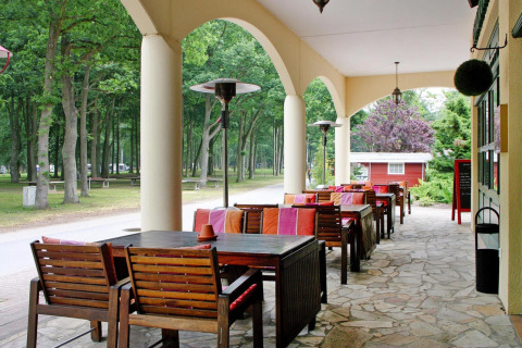 Overdekt terras met houten tafels en kleurrijke stoelen aan Holiday park Markgrafenheide Warnemünde, Duitsland.