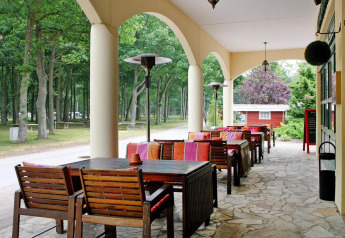 Overdekt terras met houten tafels en kleurrijke stoelen aan Holiday park Markgrafenheide Warnemünde, Duitsland.