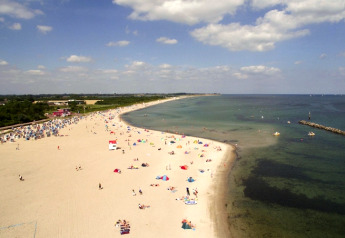 Vista de la playa desde Blockhouse «HiPr 4 Pers» en Alemania, con gente y agua azul clara.