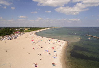 Vista della spiaggia dal Blockhouse «HiPr 4 Pers» in Germania, con persone e acqua limpida.