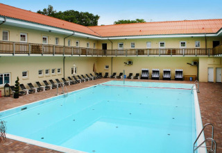 Outdoor swimming pool with sun loungers at Holiday park 'Markgrafenheide Warnemünde Type 1' in Germany.