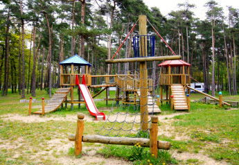 Parco giochi in legno con scivolo e rete da arrampicata a Holiday park Markgrafenheide Warnemünde, Germania.