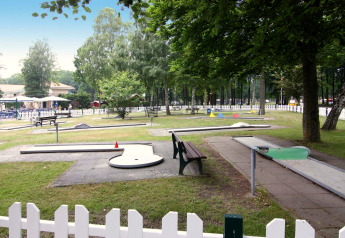 Campo da minigolf all’aperto presso Holiday park Markgrafenheide Warnemünde, circondato da alberi e recinzioni bianche.