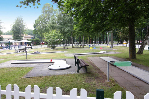 Campo de minigolf al aire libre en Holiday park Markgrafenheide Warnemünde, rodeado de árboles y vallas blancas.