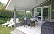 Terraza cubierta con mesa de comedor, sillas y tumbonas en Holiday home en Hünning, Alemania.