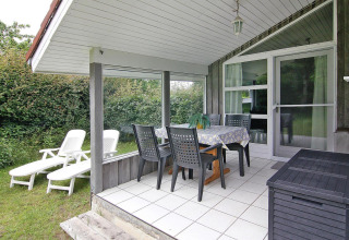 Terrazza coperta con tavolo da pranzo, sedie e lettini al Holiday home a Hünning, Germania.