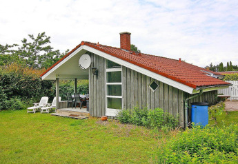 Charmante maison de vacances à Hünning, Allemagne, avec toit rouge, terrasse couverte et jardin vert.