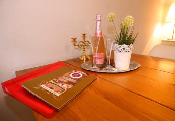 Table chaleureuse au Holiday home «in Hünning», Allemagne, avec vin pétillant, verres, plante et bougeoir.