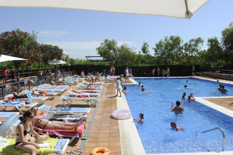 Zona de piscina en Camping del Mar MOBILE HOME 6P en España, con tumbonas, familias y niños disfrutando.