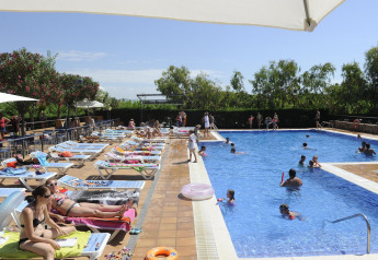 Zona de piscina en Camping del Mar MOBILE HOME 6P en España, con tumbonas, familias y niños disfrutando.