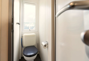 Toilet in een stacaravan op Camping del Mar in Spanje, gezien vanaf de deur met raam en toiletpapier.