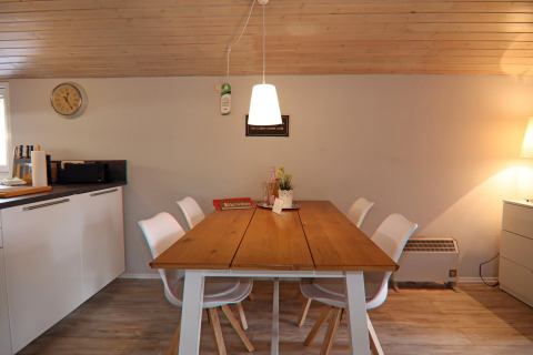 Zona pranzo in un lodge con soffitto in legno, tavolo moderno e sedie bianche a Hünning, Germania.