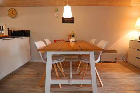Zona pranzo nella casa vacanze «in Hünning», Germania, con tavolo in legno, sedie bianche e luce calda.