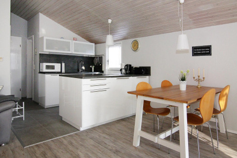 Moderne køkken og spisestue med træmøbler og hvide elementer i Holiday home «in Hünning», Tyskland.