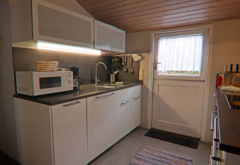 Cucina moderna in casa vacanze a Hünning, Germania, con microonde, lavello e mobili bianchi.