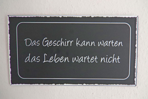 Un cartel con la frase 'Das Geschirr kann warten das Leben wartet nicht' en una casa vacacional en Hünning.