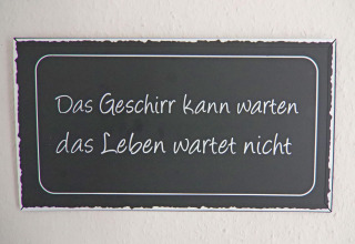 Een bordje met de tekst 'Das Geschirr kann warten das Leben wartet nicht' in een vakantiewoning in Hünning.