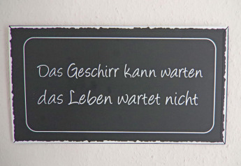 Un panneau avec l’inscription 'Das Geschirr kann warten das Leben wartet nicht' dans une maison de vacances à Hünning.