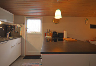 Cucina moderna nel Holiday home «in Hünning», Germania, con mobili bianchi e soffitto in legno.