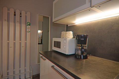 Kitchen space with coffee maker, microwave, and plates under cabinet lighting in a holiday home in Hünning.
