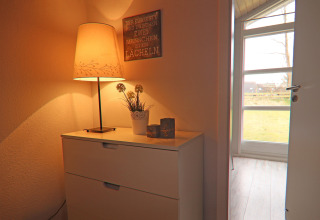 En hyggelig krog i et feriehus i Hünning, Tyskland, med en lampe, kommode og blomsterpotte.