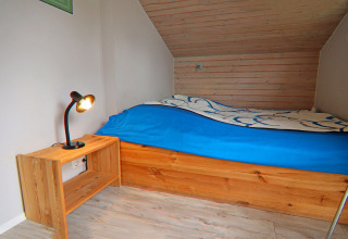 Camera accogliente presso Holiday home «in Hünning» in Germania con letto singolo e comodino in legno.
