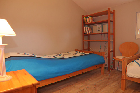Cozy bedroom at Holiday home in Hünning, Germany, featuring twin beds, a bookshelf and a chair.