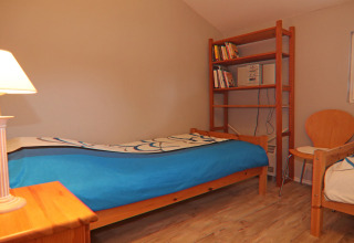 Habitación acogedora en Holiday home en Hünning, Alemania, con dos camas, estantería y silla.