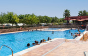 Familias y niños disfrutan de un día soleado en la piscina del Camping del Mar BUNGALOW PREMIUM en España.