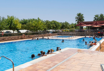 Familias y niños disfrutan de un día soleado en la piscina del Camping del Mar BUNGALOW PREMIUM en España.