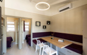 Modernes Esszimmer mit Holztisch, lila Eckbank und weißen Stühlen im Camping del Mar BUNGALOW PREMIUM, Spanien.