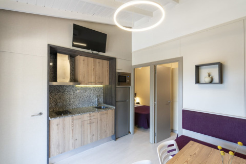 Moderne Küchenzeile und Essbereich im Camping del Mar Bungalow Premium in Spanien mit Schlafraum im Hintergrund.