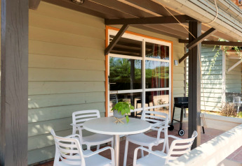 Terrasse beim Camping del Mar BUNGALOW PREMIUM in Spanien mit Tisch, Stühlen und Grill.