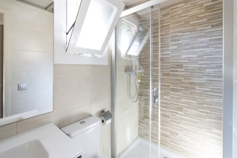 Modernes Badezimmer im Camping del Mar BUNGALOW PREMIUM in Spanien mit Dusche und geöffneten Fenstern.