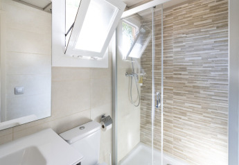 Baño moderno en Camping del Mar BUNGALOW PREMIUM en España, con ducha y ventanas abiertas.