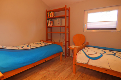 Habitación con dos camas individuales, estantería, silla y ventana en Holiday home «in Hünning», Alemania.