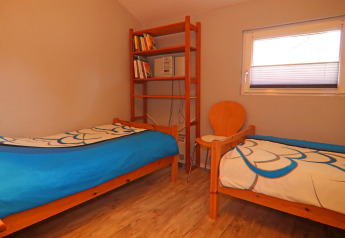 Camera con due letti singoli, libreria, sedia e finestra nell'Holiday home «in Hünning» in Germania.